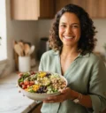 Mulher sorridente segurando uma salada colorida na cozinha